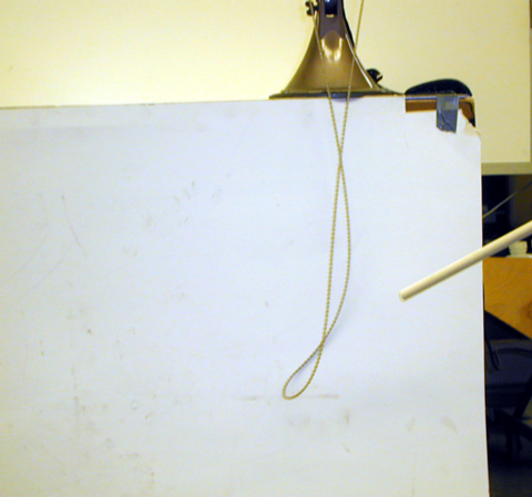 person using a dowel  to point to a chain on a white background