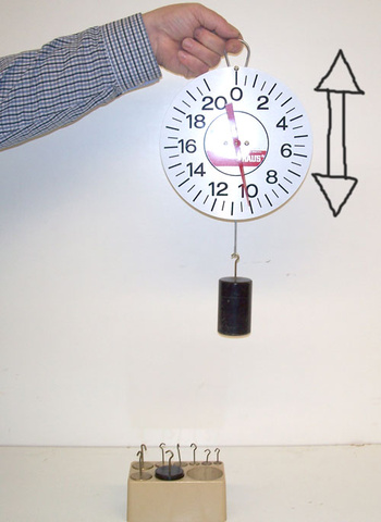 person holding a scale with a suspended weight