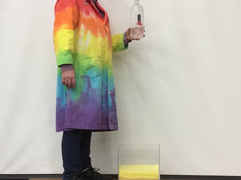 person in colorful lab coat holding a Cartesian diver bottle above a catch box