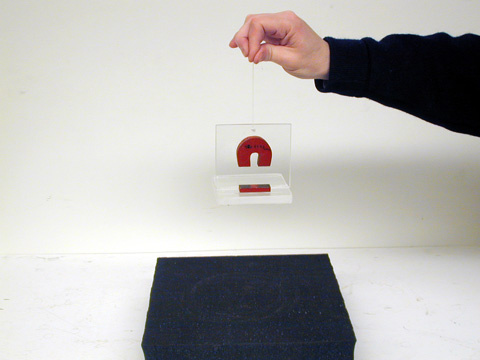person holding a magnet glued to Plexiglass holder over a foam pad.
