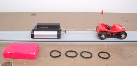 Tumble Buggy without rubber track on the wheels, Pasco Dynamics Cart with friction attachment, 3 large weights for the Pasco Cart, block.