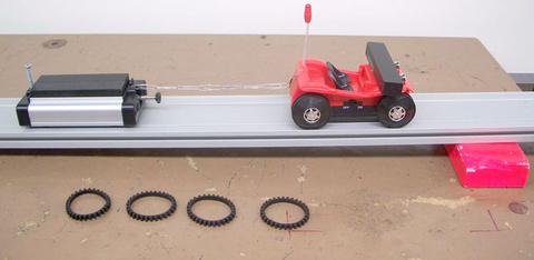 Tumble Buggy without rubber track on the wheels, Pasco Dynamics Cart with friction attachment, weights for the Pasco Cart, block under the track.