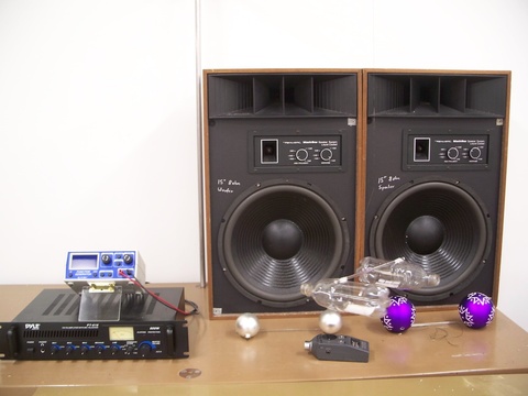 Soda bottles hanging in front of two large speakers - 1Q40.89b.jpg