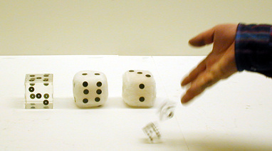 three dice, a hand throwing dice on a table