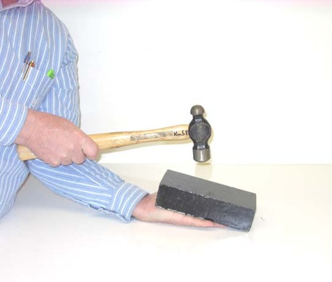 person holding a lead brick and a hammer