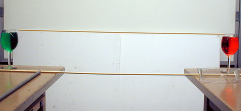 Wine glasses with colored water, wooden dowels on two tables