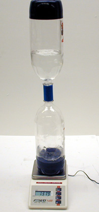 "Hourglass" made of two soda bottles (half filled with water) connected by a tornado tube on a digital scale