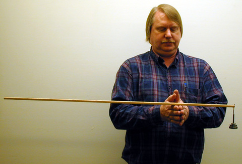 person holding a meter stick with two fingers together