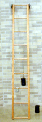 Ladder against a wall with rollers on one end, slotted weights and hanger