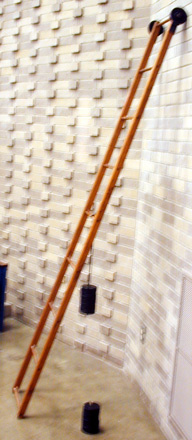 Ladder against a wall with rollers on one end, slotted weights and hanger