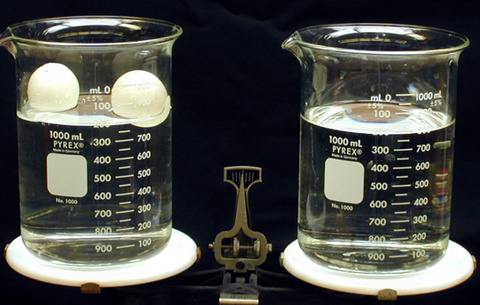 Beakers with water and ping pong balls on a scale 