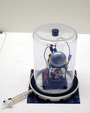 Bell jar with sorbothane pad, vacuum pump, 6 volt battery with attached doorbell.