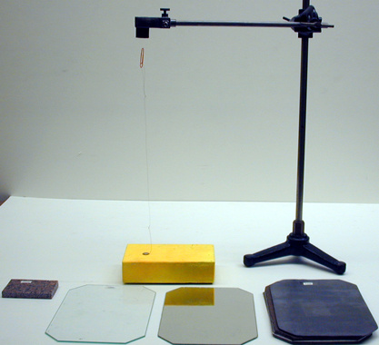 Wooden block with attached paper clip, plates, granite block, magnet.